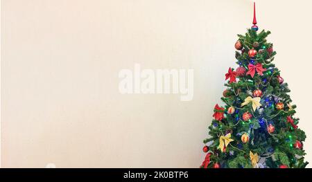 Uno scatto festivo di un albero di Natale con ornamenti colorati, evidenziato su uno sfondo bianco con una copia dello spazio a sinistra. Foto Stock