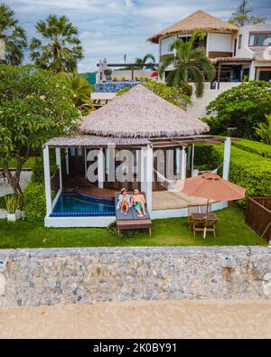 Coppia in villa di lusso godendosi nella piscina di tuffo che guarda fuori sull'oceano e sulla spiaggia in una vacanza di lusso. Uomini e donne in vacanza rilassarsi davanti alla loro villa piscina Foto Stock