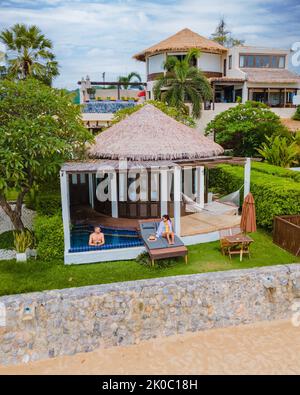 Coppia in villa di lusso godendosi nella piscina di tuffo che guarda fuori sull'oceano e sulla spiaggia in una vacanza di lusso. Uomini e donne in vacanza rilassarsi davanti alla loro villa piscina Foto Stock