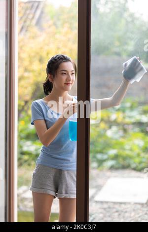 Giovane donna cinese allegra che fa i lavori di casa Foto Stock