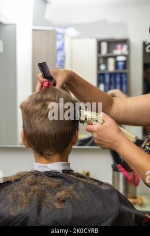 Un bel ragazzo europeo che si è acconciato al barbiere. Il parrucchiere crea un'acconciatura per un ragazzo. Foto Stock