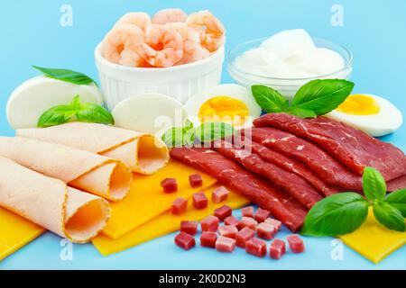 Vari alimenti con proteine su sfondo blu Foto Stock