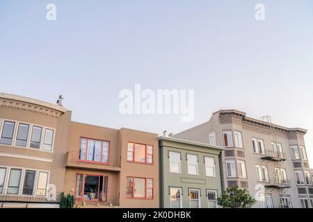 Fila di case cittadine e appartamenti con esterni in stile vittoriano a San Francisco, California. Ci case a sinistra con balconi assediati Foto Stock