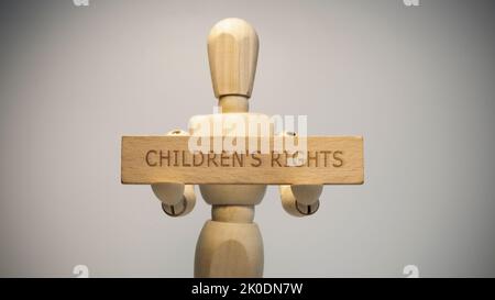 Uomo di legno che tiene in mano scritto diritti dei bambini segno su di esso. Questioni sociali. Foto Stock