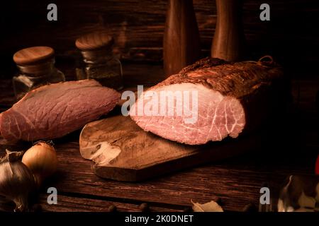 Carne su un tavolo di legno con aggiunta di erbe fresche e spezie aromatiche. Prodotto naturale di fattoria biologica, prodotto con metodi tradizionali Foto Stock