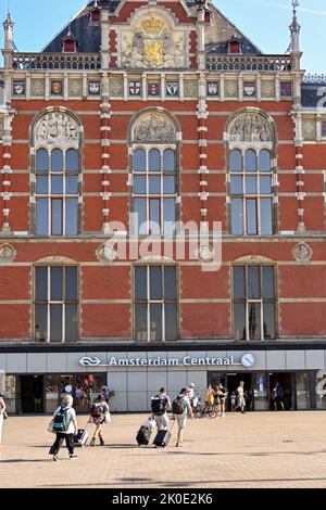 Amsterdam, Paesi Bassi - 2022 agosto: Persone che camminano verso l'ingresso della stazione ferroviaria centrale di Amsterdam Foto Stock