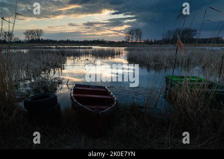 Piccole barche sulla riva del lago in una serata nuvolosa Foto Stock