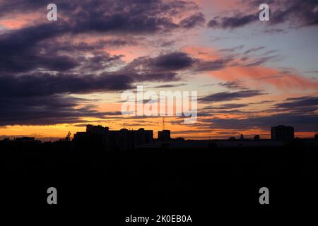 Sole che sorge sulla città Ucraina Sumy. Bella silhouette paesaggio in luci al tramonto di Sumy città, Ucraina. Meravigliose nuvole di colore Foto Stock