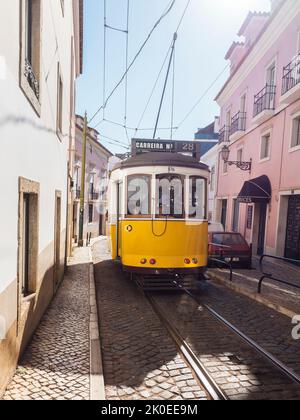 Lisbona, Portogallo, 24 ottobre 2021: Vista ravvicinata della tipica linea gialla del tram vintage numero 28 che scende lungo la stretta e ripida strada di Lisbona con, icona e. Foto Stock