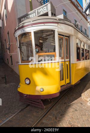 Lisbona, Portogallo, 24 ottobre 2021: Vista ravvicinata della tipica linea gialla del tram vintage numero 28 che scende lungo la stretta e ripida strada di Lisbona con, icona e. Foto Stock