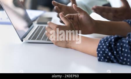 Mani di dipendenti di sesso maschile e femminile seduti al tavolo di lavoro Foto Stock