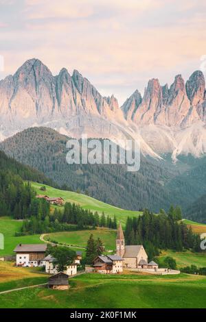 Splendida vista sulla Val di Funes con la Chiesa di Santa Maddalena e la catena montuosa del Parco Naturale Puez Odle in lontananza Foto Stock