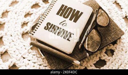 How to survive words on cover of copybook, glasses and pen. Surcvival concept. Crisis management business concept. Coronavirus prevention concept. Foto Stock