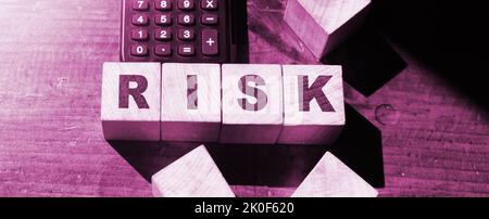 PAROLA DI RISCHIO scritta su cubi di legno e calcolatrice. Concetto aziendale di valutazione del rischio finanziario, ricompensa del rischio e gestione del rischio di portafoglio. Foto Stock