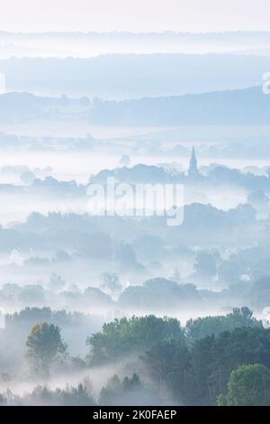 Il campanile della chiesa di St Barnabas a Weeton è prominente tra i paesaggi rurali stratificati dei pascoli di Arthington in una mattina d'autunno misteriosa. Foto Stock