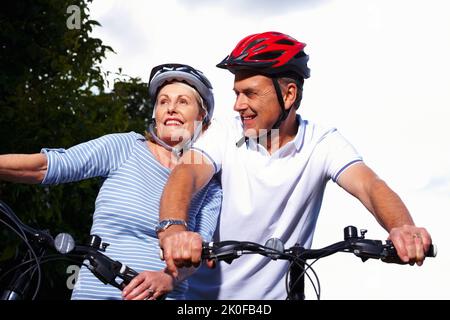 Uomo e donna sportivi maturi in bicicletta in una giornata di sole. Ritratto di un uomo sportivo maturo e di una donna in bicicletta in una giornata di sole. Foto Stock