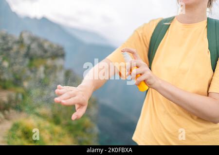 Donna che applica repellente insetto contro zanzara e zecca sulla sua mano durante l'escursione in montagna natura. Protezione della pelle contro il morso di insetto Foto Stock