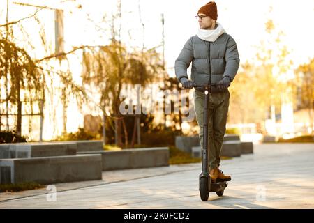 Giovane uomo in abiti caldi in moto lungo la strada nel giorno d'autunno Foto Stock