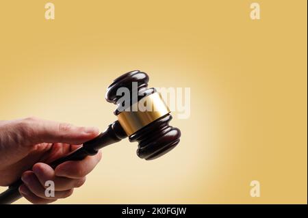 La Gavel del giudice di legno in mano di un uomo su uno sfondo beige. Simbolo del giudizio e della giustizia. Diritto, Stato di diritto, asta. Minimalismo. C'è spazio libero Foto Stock