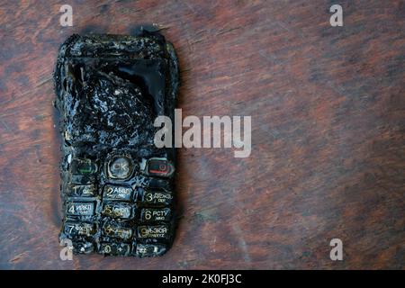il telefono cellulare bruciato si trova sul tavolo Foto Stock