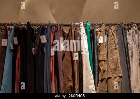 Fila di jeans in tessuto color terra o jeans pantaloni denim e slacks appendono su appendiabiti. Vari pantaloni nel negozio di moda. Stile retrò di seconda mano o Foto Stock