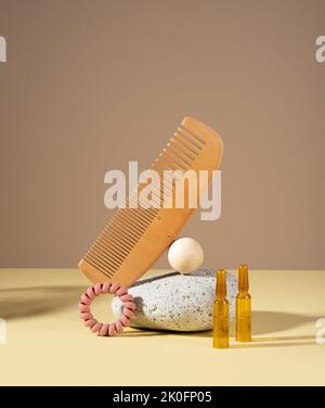 Fiale cosmetiche con siero per la crescita dei capelli, il ripristino. Pettine per capelli e pietra su sfondo chiaro. Concetto bellezza capelli, cura di sé, spa e benessere Foto Stock