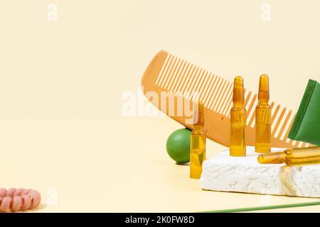 Fiale cosmetiche con siero per la crescita dei capelli, il ripristino. Pettine per capelli e puntine verdi su sfondo beige. Concetto bellezza capelli, cura di sé Foto Stock