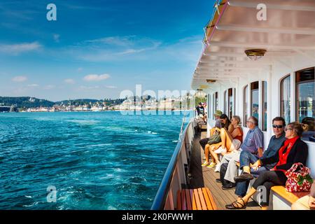 Le persone che si godono un giro in barca a vapore sul Lago di Lucerna con la città sullo sfondo, Lucerna, Svizzera Foto Stock