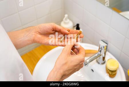 Mani maschili che tengono fiale cosmetiche con siero per la crescita dei capelli, ripristino bellezza capelli in un bagno moderno e luminoso. Perdita dei capelli di concetto Foto Stock