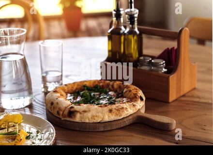 Pizza su tavolo di legno in stile vintage. Sfondo ristorante italiano per il vostro design. Stile di vita del ristorante. Concetto di cibo. Foto Stock