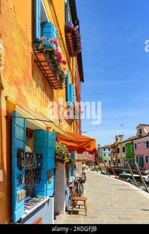 ISOLA DI BURANO, VENEZIA, ITALIA - 4 LUGLIO 2022: Biciclette parcheggiate di fronte ad un negozio di souvenir dai colori vivaci. Case colorate nell'Isola di Burano. Famoso tr Foto Stock