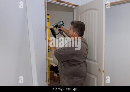 Durante l'installazione delle porte interne in una nuova casa, un falegname di rivestimento installa le porte Foto Stock