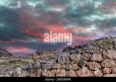 018 01 05  Myceane Grecia - i turisti salgono le antiche mura che i miti pretende furono costruite dai giganti sotto il cielo fuoco del tramonto - reperti archeologici qui p Foto Stock