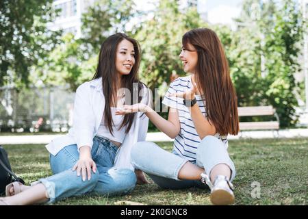 Giovani belle ragazze asiatiche con capelli lunghi in abiti casual, amici che si divertono nel parco cittadino Foto Stock