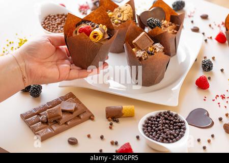 Cupcake al cioccolato.appetitose cupcake al muffin in mano sul tavolo con dolci e pasticceria.dessert al cioccolato. Dolci assortiti. Dolci e dessert Foto Stock