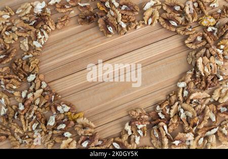 Fresco nocciole su sfondo di legno con spazio copia in una forma di cuore. Concetto di benefici per i noccioli di noce. Foto Stock
