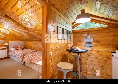 Piccola cucina elegante e accogliente camera da letto in casa di legno. Concetto di vita di villaggio. Foto Stock