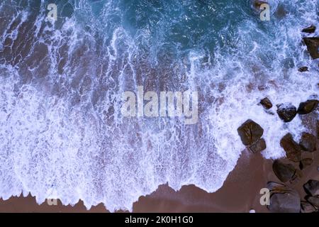 Vista aerea onde che si schiantano sulla sabbia della spiaggia e sfondo di onde morbide, vista dall'alto fondale di sabbia di mare scuro Foto Stock