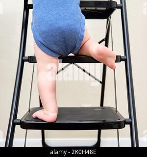 Il bambino sale sulla scala dei gradini. Bambino ragazzo sale le scale, scala. Bambino di un anno Foto Stock