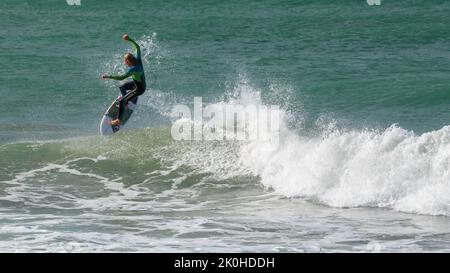 Un surfista che si lancia nell'aria da un'onda di rottura. Monte Maunganui, Nuova Zelanda Foto Stock