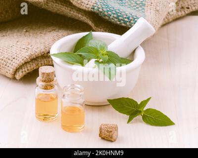 Concetto di medicina alternativa - olio di basilico di limone ingredienti naturali per aromaterapia con mortaio e pestello Foto Stock