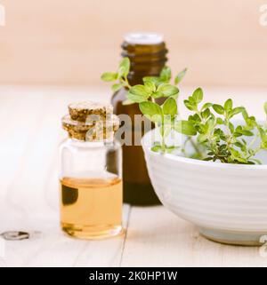Un primo piano di bottiglie di olio essenziale e foglia di timo di limone su fondo ligneo Foto Stock