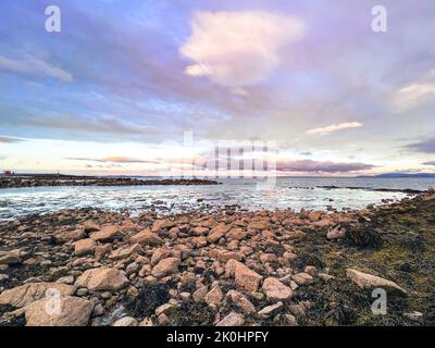 La splendida vista sul mare con spiaggia rocciosa a Salthill Promenade Galway, Irlanda sotto il cielo colorato tramonto nuvoloso Foto Stock