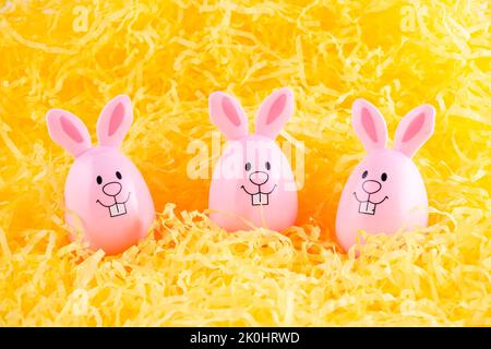 Il coniglietto rosa dell'uovo di Pasqua è circondato da ciocche di carta giallo brillante Foto Stock