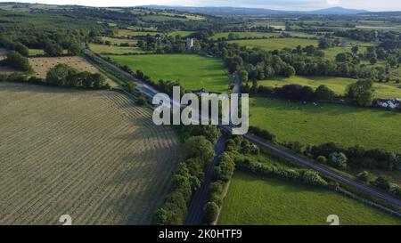 Un colpo di drone di una strada tra i campi e le rovine dell'abbazia di Jerpoint a Thomastown, contea di Kilkenny Foto Stock