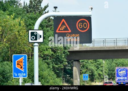 Cartello autostradale a pannello singolo M25 sopra la corsia un LIMITE di velocità variabile 60mph & Queue ahead message & Smart Lane layby Half Mile & standard camera signs UK Foto Stock