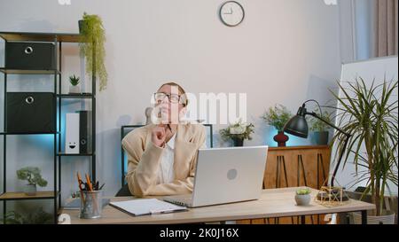 Una donna d'affari freelancer entra in ufficio, lavorando sul computer portatile alla scrivania. Professionista manager freelance donna lavora su notebook, invia messaggi fare acquisti online guardare film Foto Stock