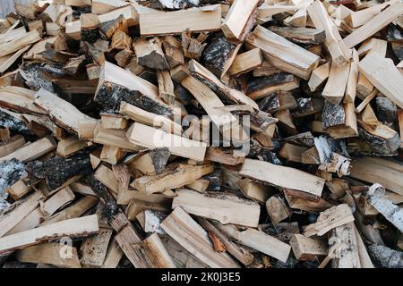 Legna da ardere di betulla struttura del palo, spaccata con pezzi di ascia accatastati in un mucchio grande. Alto e largo. Foto Stock