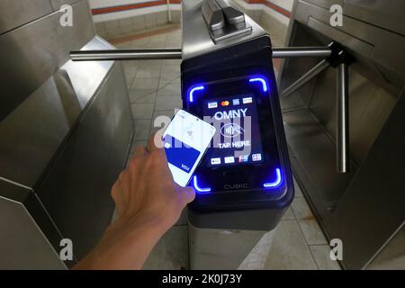 Uno smartphone con Google Wallet tocca un tornello della metropolitana di New York dotato di un lettore di pagamento senza contatto OMNY che accetta pagamenti NFC Foto Stock