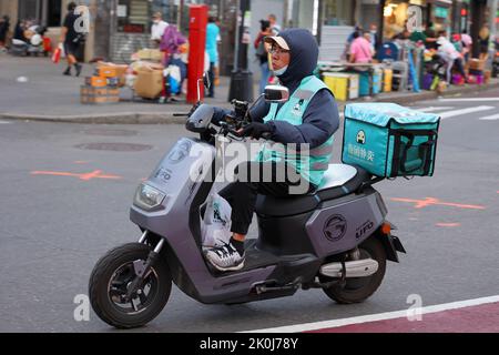 Una persona Fantuan consegna su un ciclomotore elettrico in Downtown Flushing, New York. Fantuan 飯糰外賣Asian consegna di cibo Foto Stock